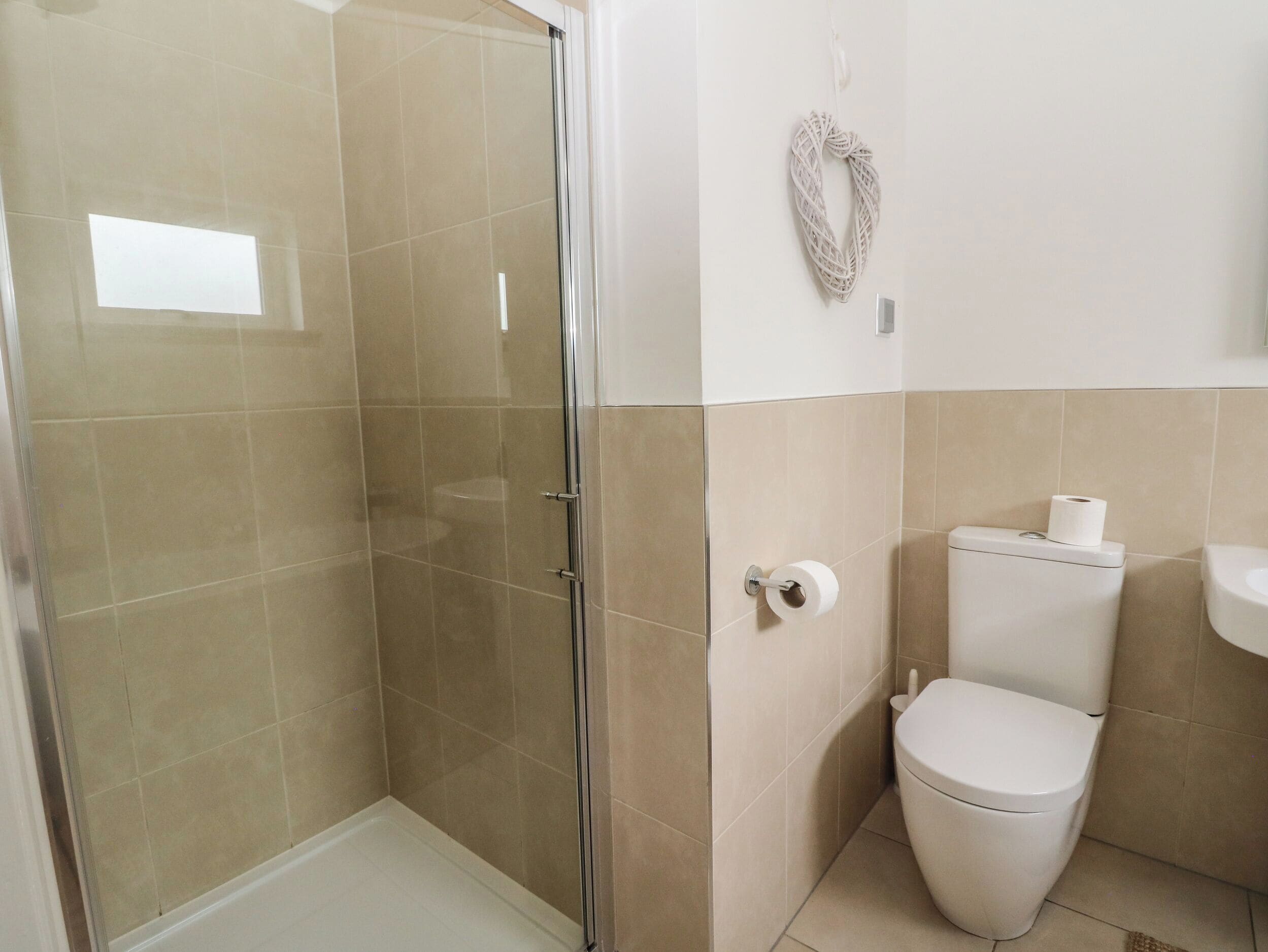 A bathroom with a glass shower enclosure, a toilet, and a sink.