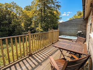 A wooden deck with a table and chairs, a hot tub, and a wooden fence. - Garth Cottage (Killin)