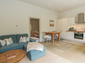 A living room with a sofa, coffee table, and a dining area with a table and chairs.