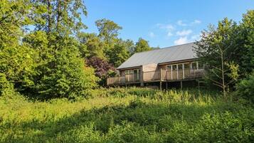 A house with a deck, surrounded by dense greenery and trees.