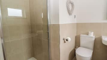Un baño con cabina de ducha de vidrio, inodoro y lavamanos.