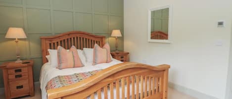 Een slaapkamer met een houten bed, twee nachtkastjes, een spiegel en een vloerbedekking.