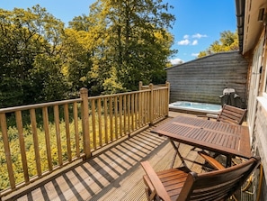 A wooden deck with a table and chairs, a hot tub, and a wooden fence. - Almond (Killin)