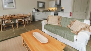 A compact living space with a dining area, kitchenette, and a sofa with a throw blanket. - Yew Tree (Killin)