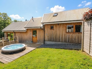 Una casa de madera con jacuzzi, patio cercado y cielo despejado.