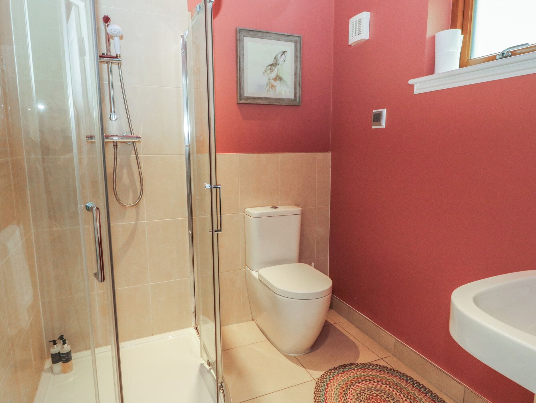 Un baño con cabina de ducha de vidrio, inodoro y lavamanos.