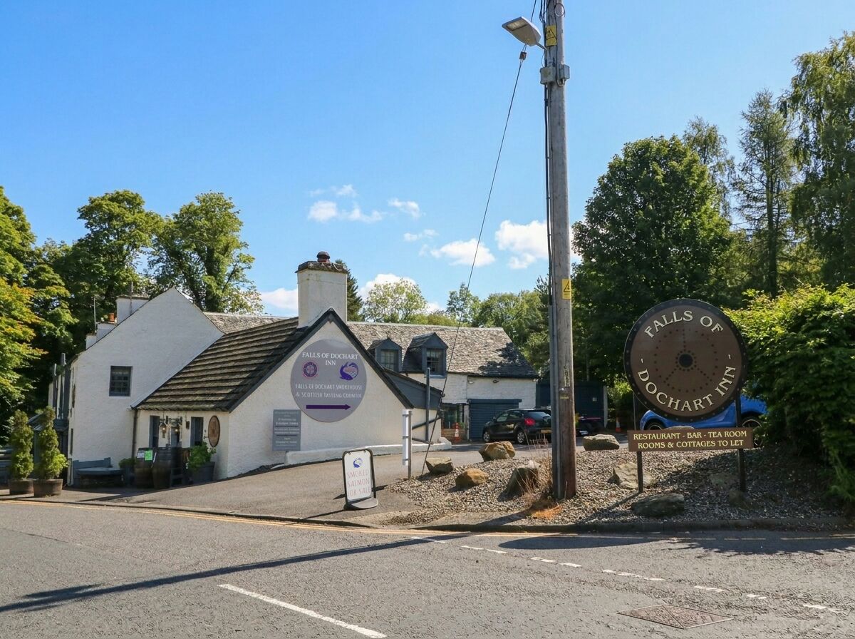 En byggnad med en skylt som visar namnet Falls of Loch Garten Inn, vilket indikerar att det är ett hotell med en restaurang, bar, tesalong samt rum och stugor som hyrs ut.