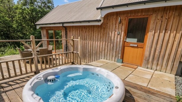 Un bain à remous sur une terrasse en bois, avec un bâtiment en bois en arrière-plan.