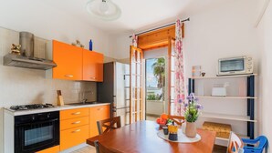 Uma cozinha com armários cor de laranja, uma mesa de jantar de madeira e um micro-ondas numa prateleira.