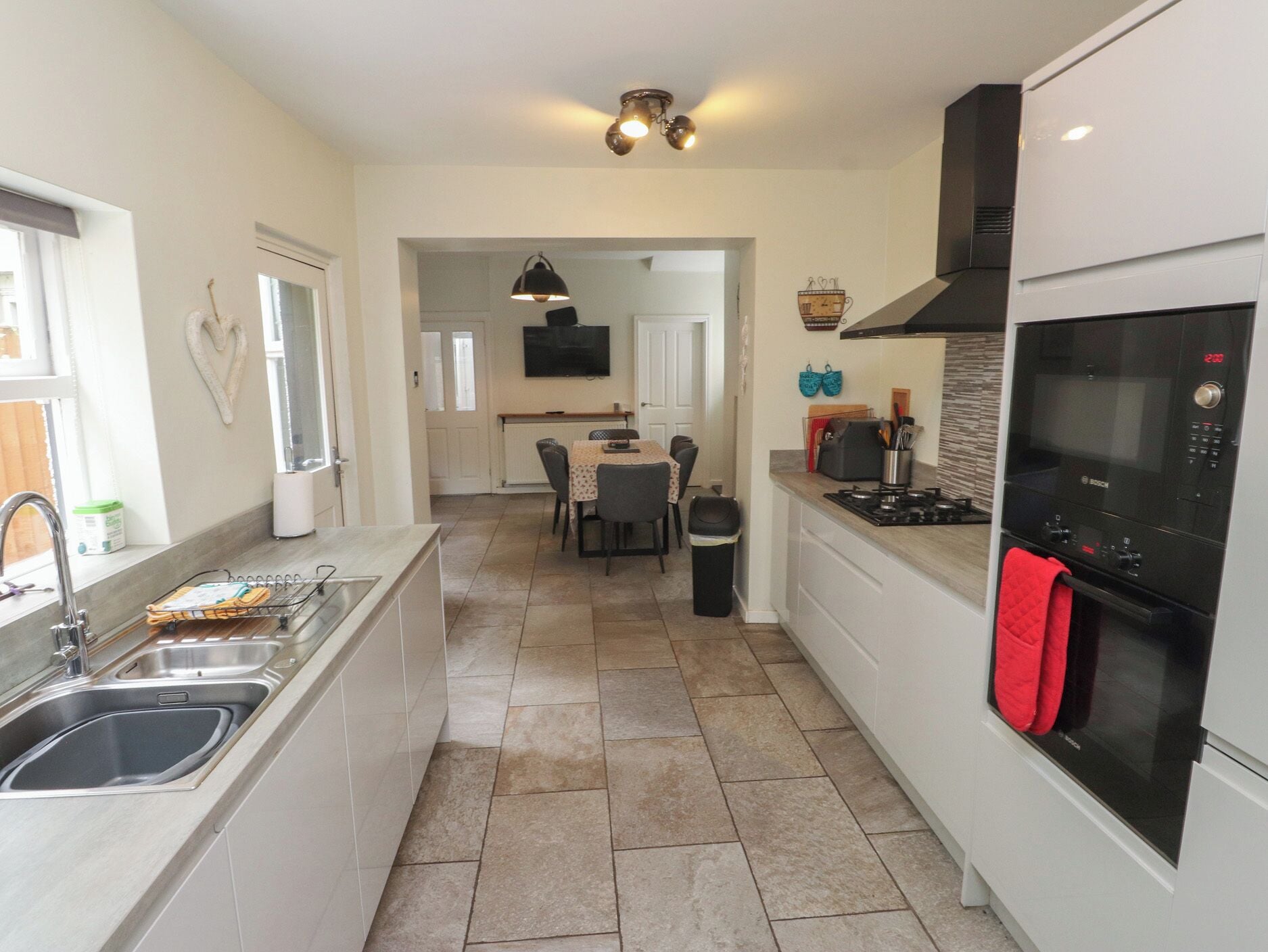 A modern kitchen with a central island, a dining area, and a view into the living room.