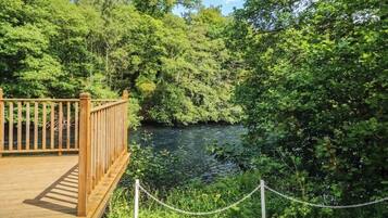 Een houten terras met uitzicht op een rivier, omringd door weelderige begroeiing.
