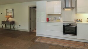 A modern kitchen with white cabinets, a built-in oven, and a gas stove. - The Crannog (Killin)
