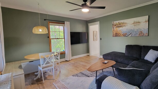 A living room with a sofa, a coffee table, a TV, a dining table with chairs, and a window with curtains. - Pet-Friendly Duluth Basecamp Near Spirit Mountain (Duluth)