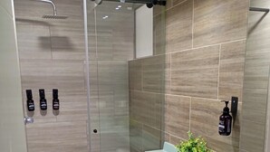 A modern bathroom with a glass shower enclosure, a white toilet, and a green sink with a potted plant. - Modern Apartment with Pool Near Unicentro Shopping Center (Neiva)