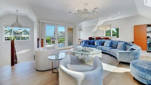 Un salon spacieux avec un grand canapé, une table basse en verre et un lustre moderne.