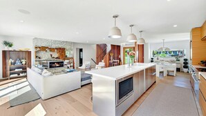 Une cuisine moderne dotée d’un îlot central, d’appareils électroménagers intégrés et de luminaires suspendus.