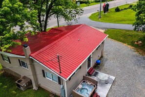 Une maison à deux étages avec un toit rouge, un jacuzzi et une allée en gravier.