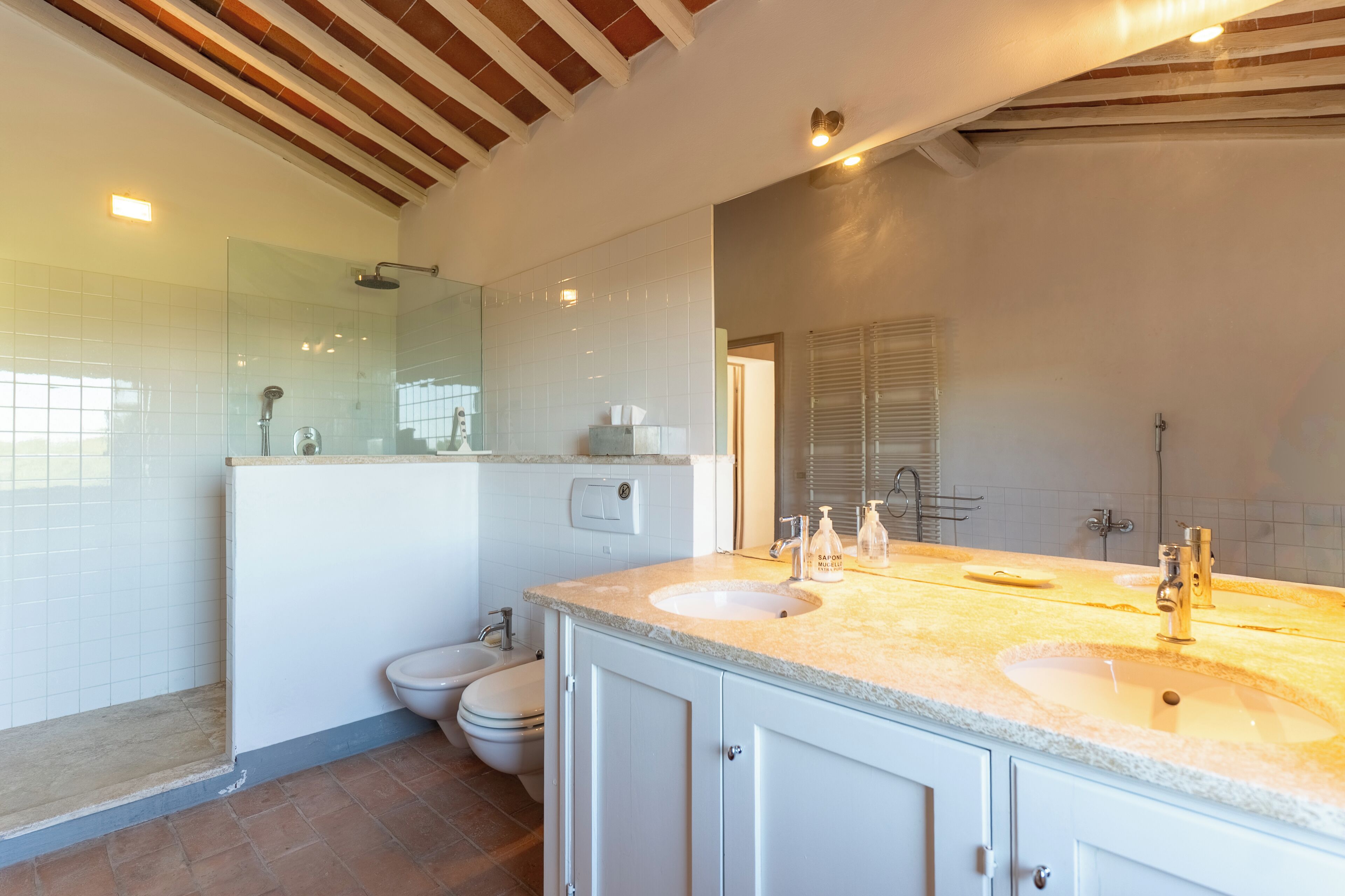 A modern bathroom with a large sink, a shower, and a toilet.