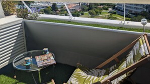 Een balkon met uitzicht op zee, een tafel met een tijdschrift en twee stoelen.