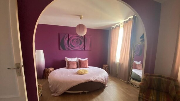 Une chambre à coucher avec un lit, une chaise et un miroir.