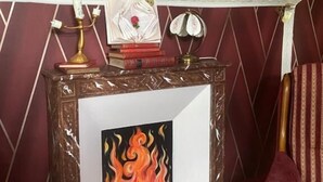 Une pièce avec une cheminée, un miroir et un fauteuil rouge.