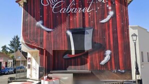 Un bâtiment orné d’une grande fresque représentant un haut-de-forme et des plumes, et sur lequel on peut lire l’inscription « CHAPEAU CLAQUE Cabaret ».