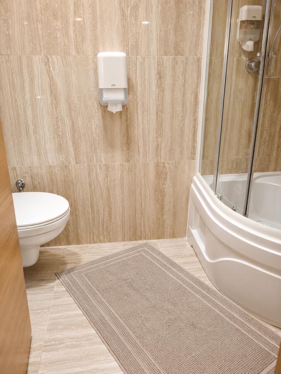 A bathroom with a toilet, a shower, and a hand dryer.