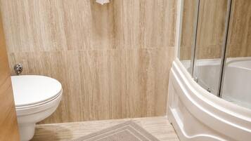 A bathroom with a toilet, a shower, and a hand dryer.