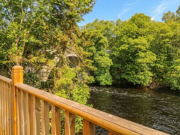 A wooden bridge over a river with dense green foliage on both sides.