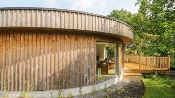A wooden cabin with a curved roof, a glass door, and a deck.