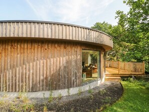 A wooden cabin with a curved roof, a glass door, and a deck. - Otters Holt (Killin)