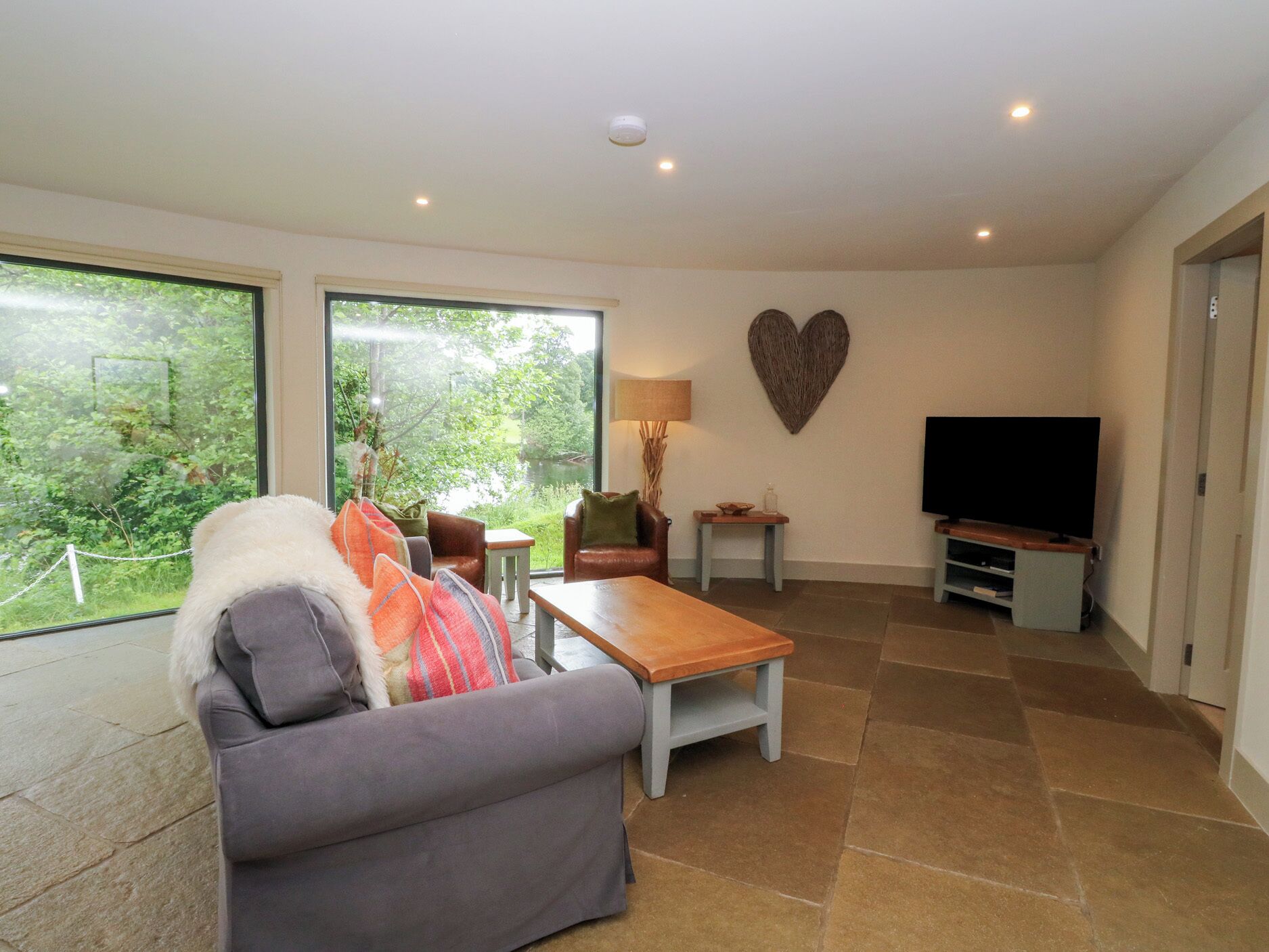 A living room with a sofa, a coffee table, a TV, and a heart-shaped wall decoration.