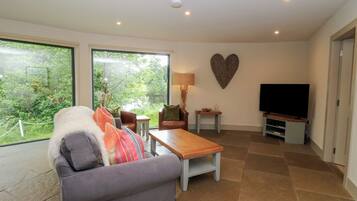A living room with a sofa, a coffee table, a TV, and a heart-shaped wall decoration.