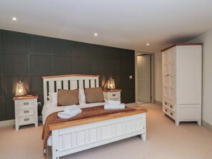 A bedroom with a bed, bedside tables, a wardrobe, and a door. - Otters Holt (Killin)