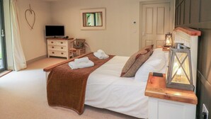 A bedroom with a bed, a TV, a dresser, a chair, and a window. - Otters Holt (Killin)