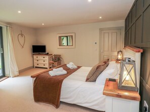 A bedroom with a bed, a TV, a dresser, a chair, and a window.