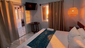 Habitación de hotel con cama, cortinas, ventilador de techo, televisión y una mesita.