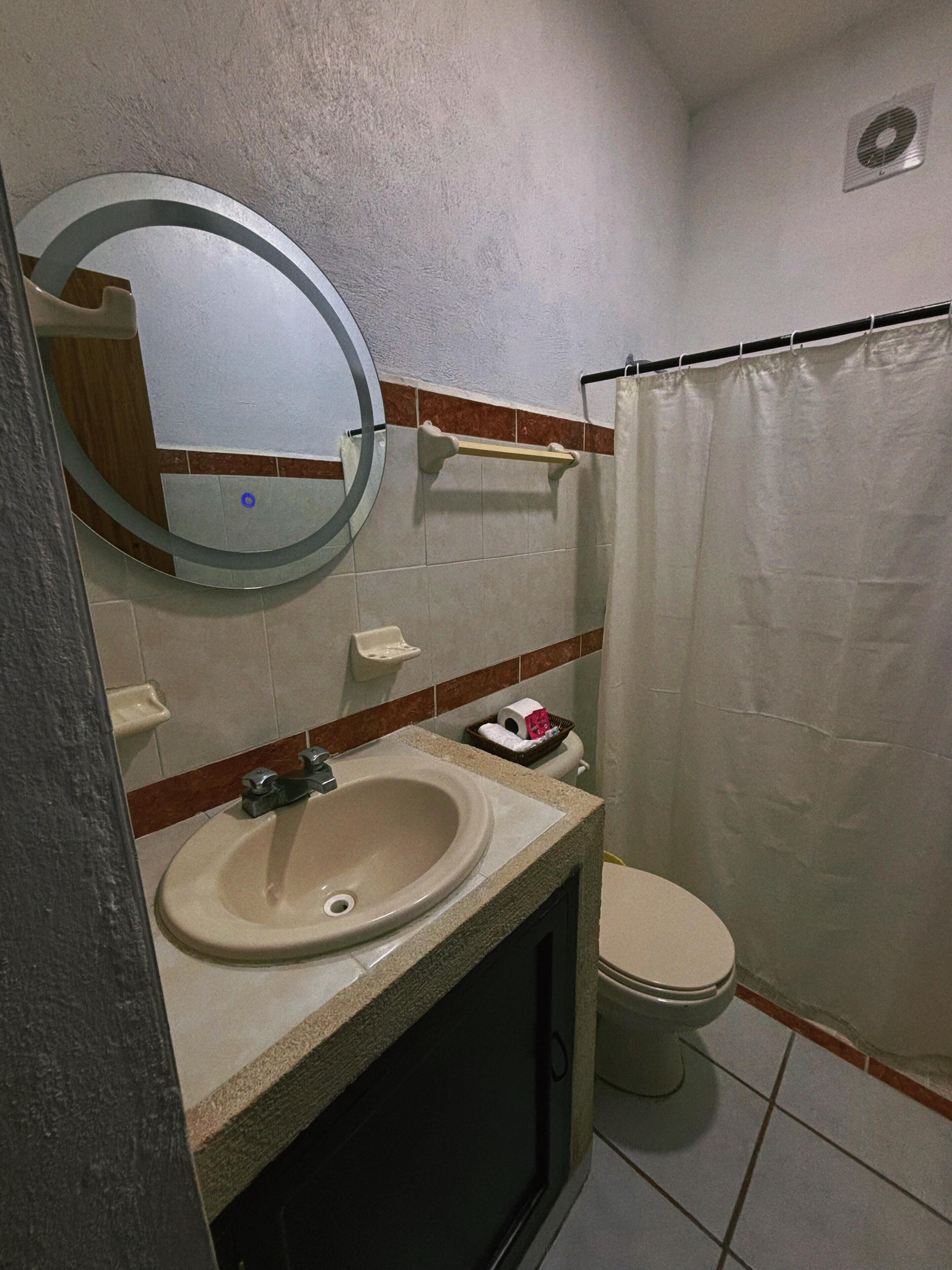 Un baño pequeño con lavamanos, inodoro y cortina de ducha.