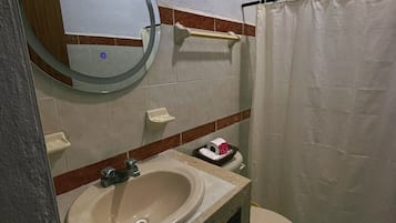 Un baño pequeño con lavamanos, inodoro y cortina de ducha.