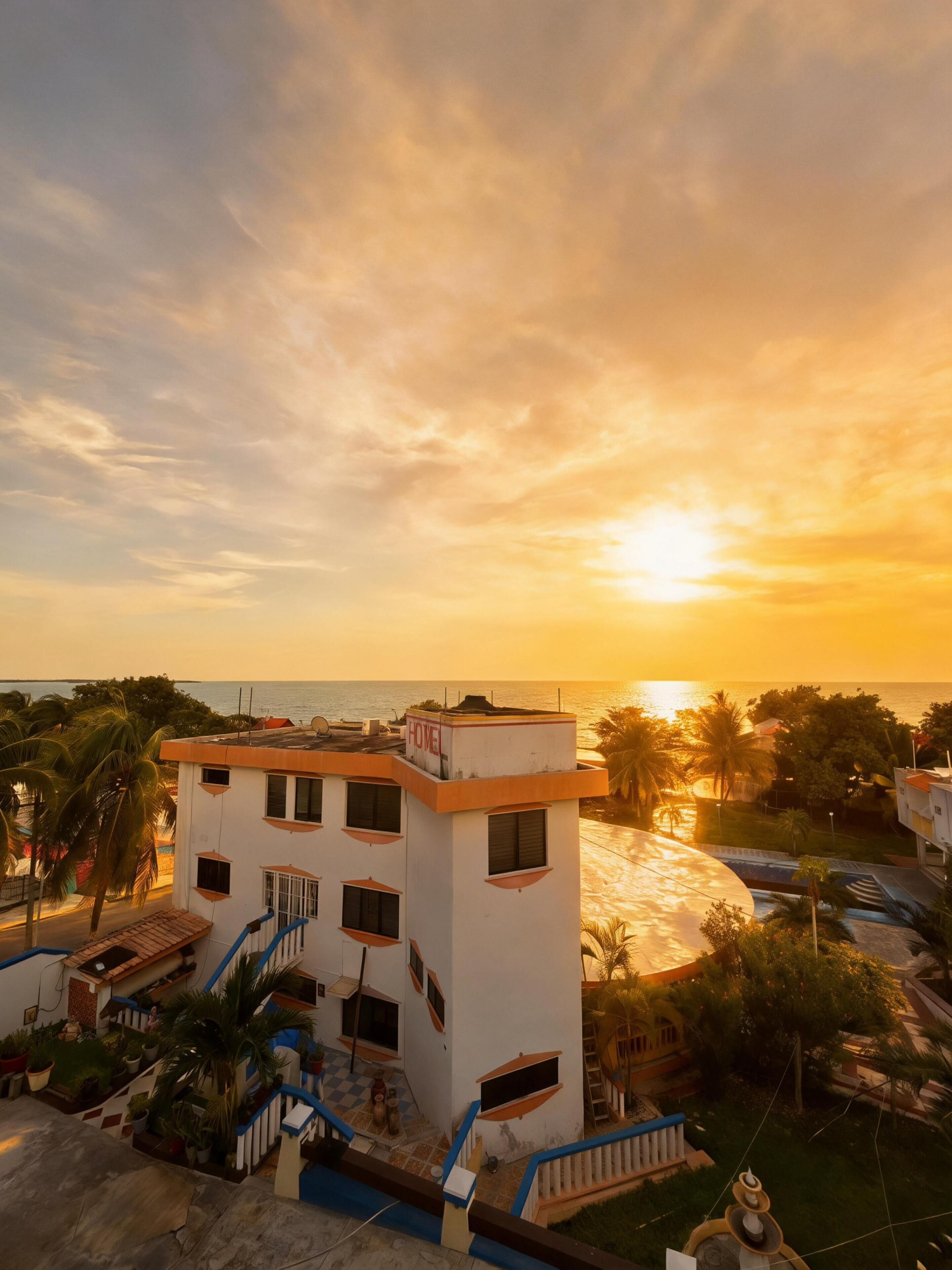 Un hotel con terraza en la azotea, piscina y vista al mar al atardecer.