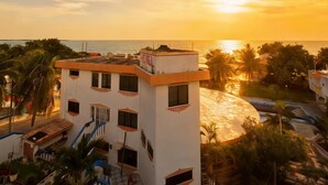 Un hotel con terraza en la azotea, piscina y vistas al atardecer sobre el mar.