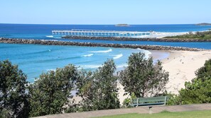 A beach with a pier extending into the ocean, surrounded by trees and a bench. - Salthill - Waterfront Pet Friendly Family Home on the Tweed River - Min 3N (Tweed Heads)