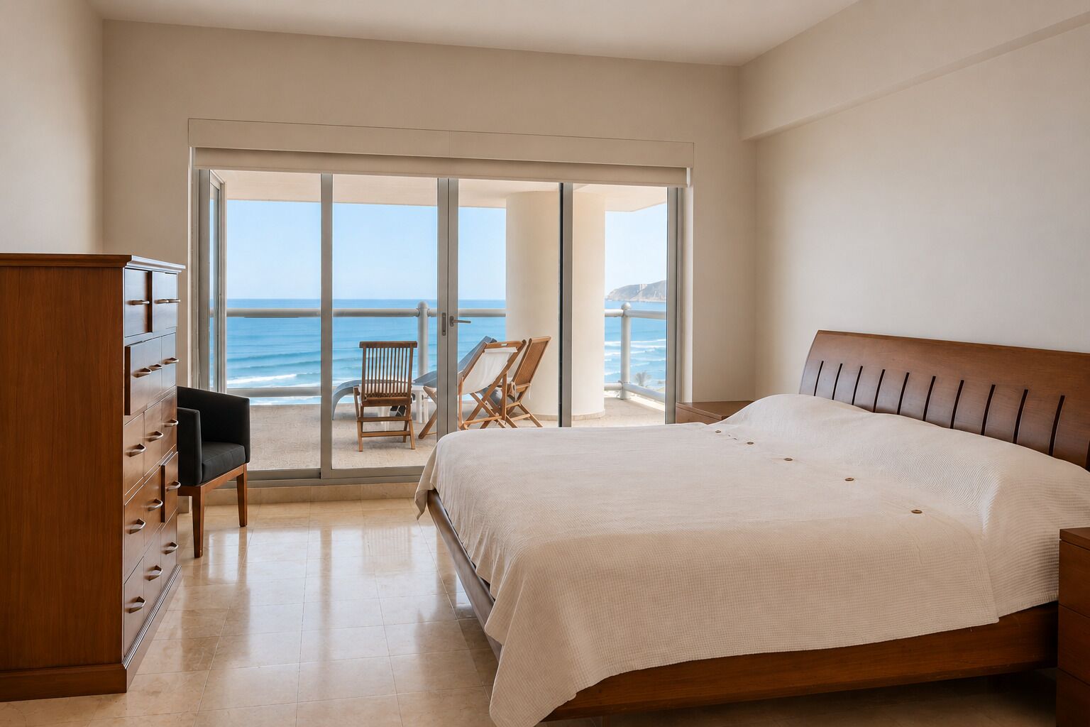 A bedroom with a large bed, a wooden dresser, and a view of the ocean through a sliding glass door.