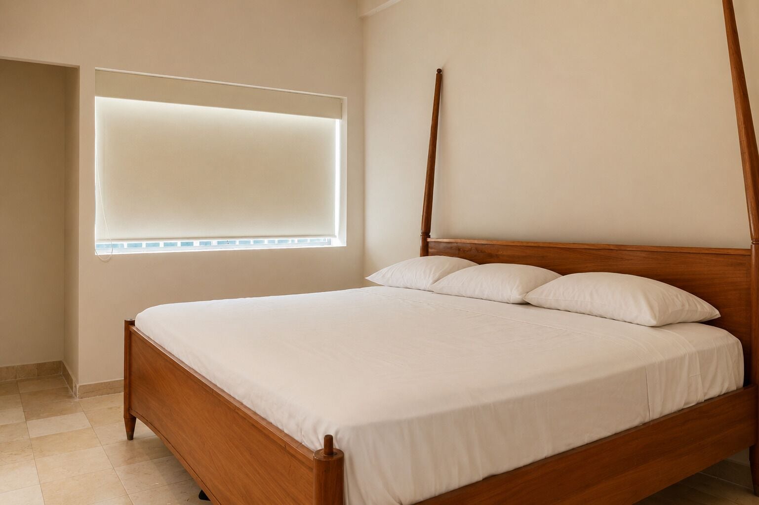A single bed with a wooden frame and white bedding in a room with a window and a door.