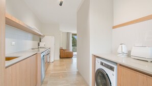 Une cuisine moderne dotée d’un lave-linge encastré, de meubles en bois et d’une grande fenêtre.