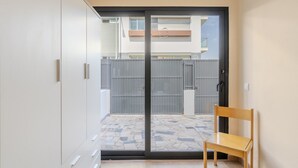Quarto com porta de correr de vidro que dá para um pátio, uma cadeira de madeira e um guarda-roupa.