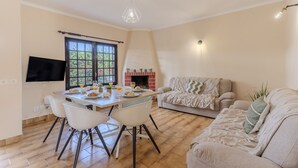 Uma sala de jantar com mesa, cadeiras, televisão, lareira e sofá.