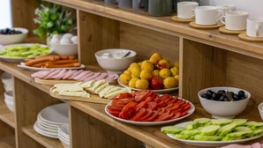 A buffet with various food items including sliced tomatoes, cucumbers, ham, and olives.