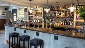 A bar area with a bar counter, stools, and a variety of bottles and glasses. - Gorgeous 2 bedroom Kintbury cottage (Kintbury)