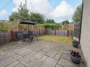 Eine Terrasse mit Tisch und Stühlen, ein Holzzaun und ein Blumentopf.
